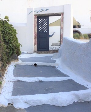 A pathway leading to a building with a black door and decorative fish motifs.
