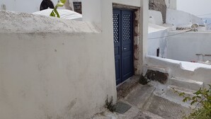 Un edificio blanco con una puerta azul, un escalón pequeño que lleva a la entrada y una antena parabólica en el techo.