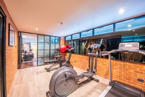 Un gimnasio con equipo de ejercicio, un espejo grande y una pared de ladrillo.
