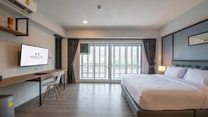 A modern hotel room with a bed, desk, and TV. - Mayson Place (Samut Prakan)