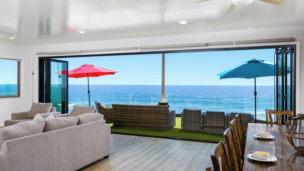 Een ruime zithoek met een grote schuifpui naar een balkon met uitzicht op de oceaan.