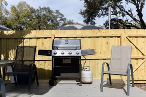 An outdoor barbecue grill with a wooden fence, a table, and two chairs. - DT home 10 min. drive from beach (Sarasota)