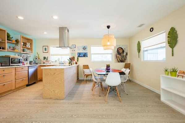Una cocina moderna con armarios de madera, una isla central y una zona de comedor con sillas blancas.