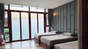 Habitación de hotel con dos camas, un amplio ventanal corredero que da a un balcón y un diseño moderno con cabecero acolchado.