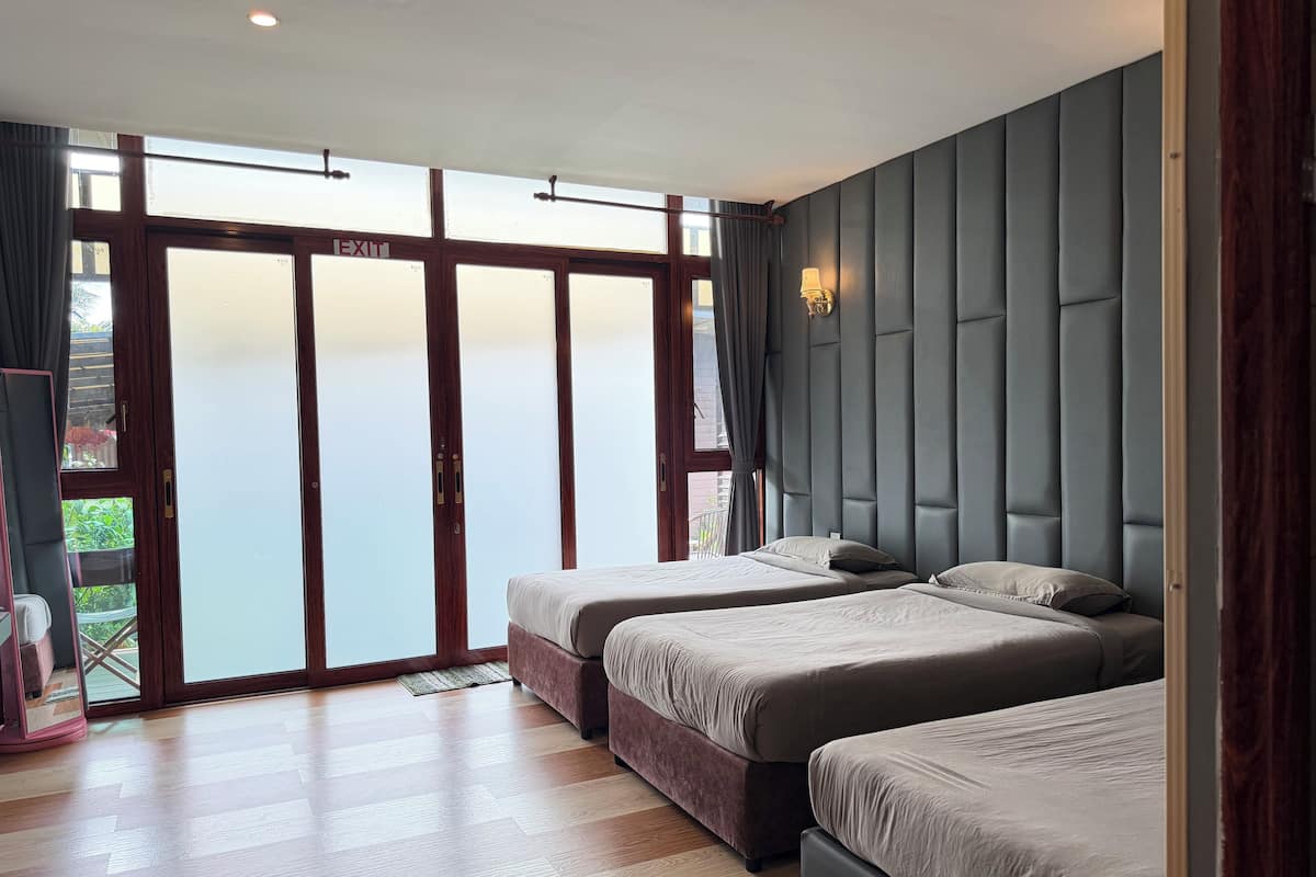 A hotel room with two beds, a large sliding glass door leading to a balcony, and a modern design with a padded headboard.