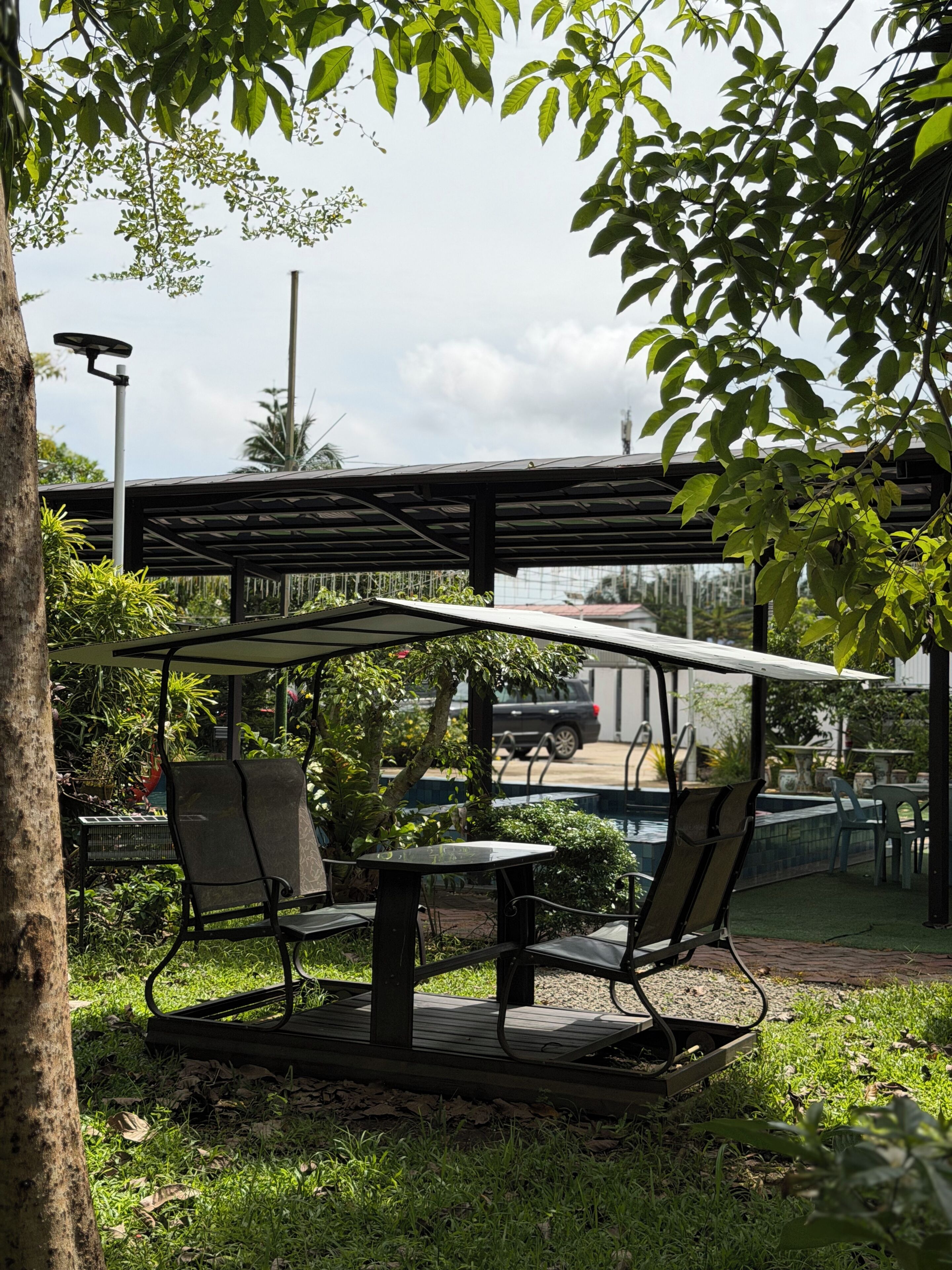 Uma área externa com assentos, incluindo uma pérgola, duas cadeiras e uma mesa.