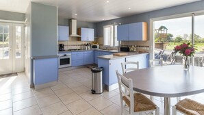 A modern kitchen with blue cabinets, a central island, and a dining area with a round table and chairs.