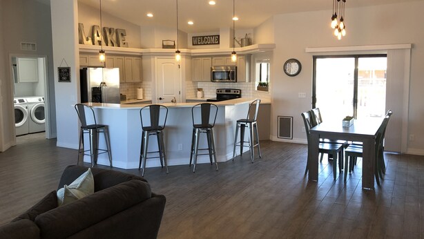 A modern kitchen with a central island, bar stools, and a dining area with a table and chairs.