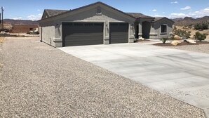 A two-story house with a garage, a driveway, and a landscaped front yard with rocks and small plants.
