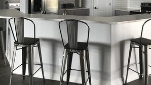 A modern kitchen with a large island, stainless steel appliances, and bar stools.
