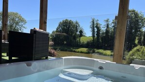 Ett bubbelbad med utsikt över en damm och träd.