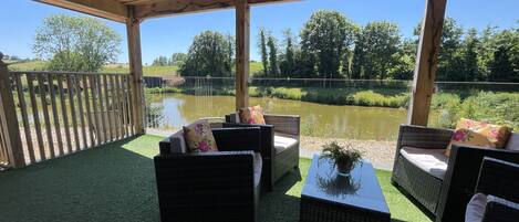 Eine Terrasse im Freien mit Korbmöbeln und Blick auf einen Teich.