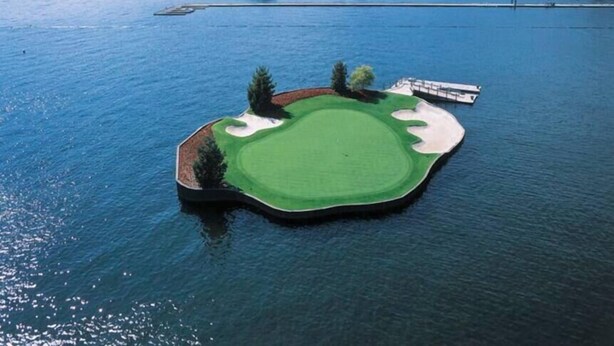 Een golfterrein eiland met bunkers en een waterpartij.