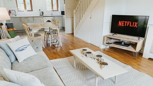 Una sala de estar moderna con un sofá, una mesa de centro y un televisor sobre un soporte de madera.