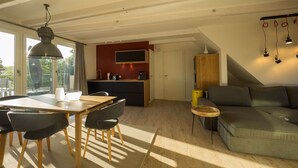 Amplia sala de estar con mesa de comedor, sillas, sofá y cocina al fondo.