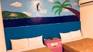 Quarto de hotel com cabeceira de tijolos azuis, duas camas com roupa de cama estampada, um minibar rosa e um mural com uma cena de praia.