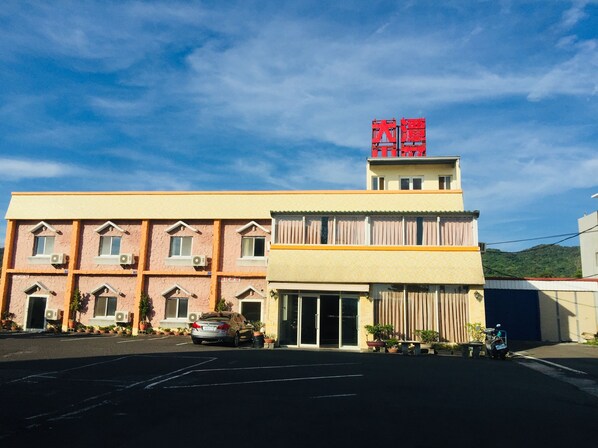 A two-story building with a flat roof, a large entrance with a glass door, and a sign with red characters on top. - Da Tan Mountain Villa (Hengchun)