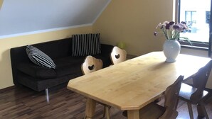 Een moderne loft met een houten eettafel, een zwart-wit gestreepte bank en een groot raam dat voor natuurlijk licht zorgt.