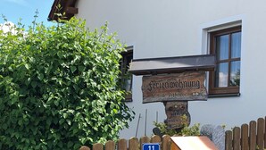Een houten bord met daarop 'Feriendorf' en 'Familie Desorbs', bevestigd aan een gebouw met een raam.