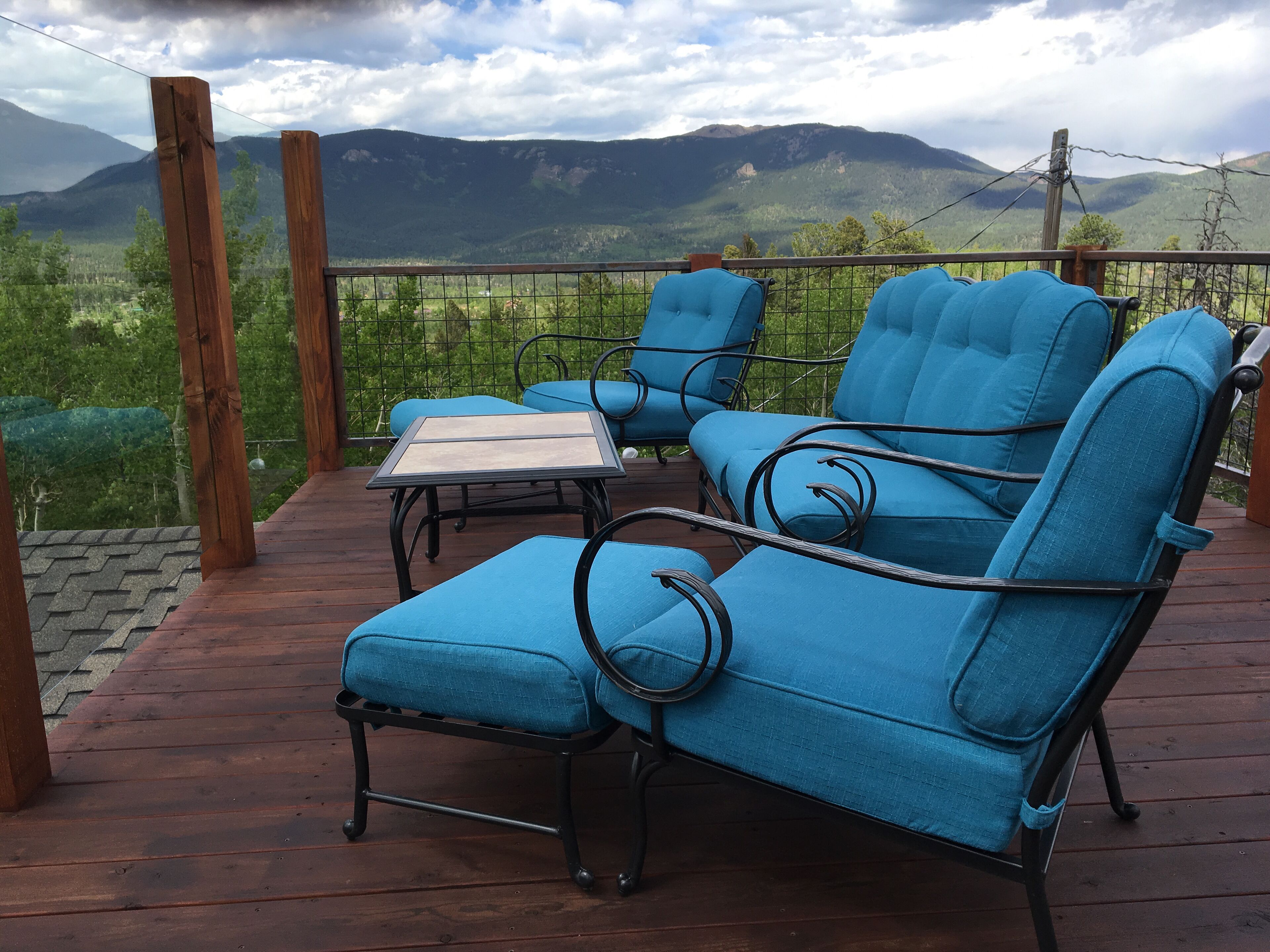 Eine Terrasse mit blauen, gepolsterten Stühlen und einem Tisch mit Blick auf eine Berglandschaft.