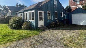 A two-story house with a blue exterior, a white garage door, and a gravel driveway.