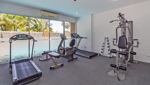 A gym with treadmills, an elliptical, and weight machines. - Chic Condo Karon by RESAVA (Karon)