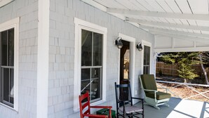A covered porch with white siding and two windows. There are three rocking chairs and a small table. - Sea Rose Cottage - Cozy, Comfortable, Ocean Views on Orr's Island, Harpswell, ME (Harpswell)