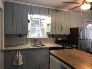 Kitchen features a classic design with light cabinets, stainless steel appliances, and a wooden countertop.