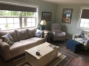 Relax in this inviting living room with a sofa, armchair, and ottoman, surrounded by a warm and cozy atmosphere.