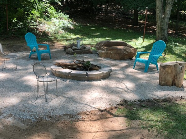 Relax by the fire pit surrounded by trees and natural scenery, with comfortable seating options available.