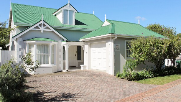 A two-story house with a green roof, white exterior, and a brick driveway. - River Club 4216 (Plettenberg Bay)