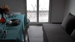 A room with a bed, a table set for two, and a sliding glass door leading to an outdoor area.