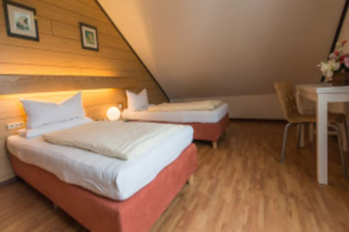 A bedroom with two beds, a wooden ceiling, and a small table with chairs.