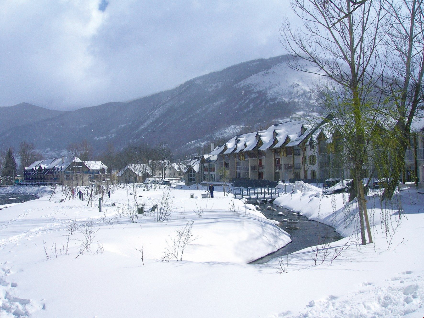 A snow-covered landscape with a building featuring multiple balconies and a ski slope.
