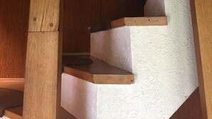 A wooden staircase with a textured wall and framed artwork.
