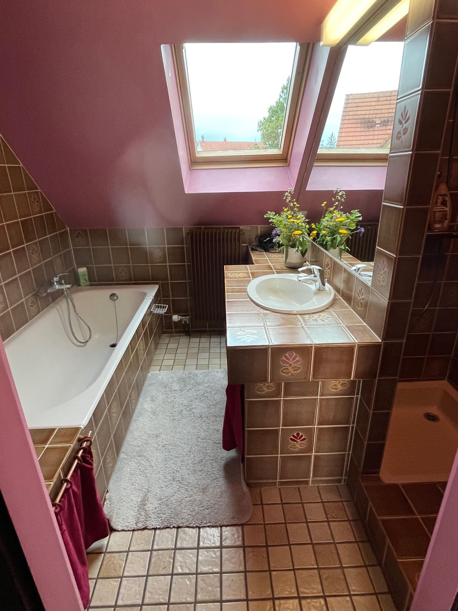 Une salle de bain avec une baignoire, un lavabo, une fenêtre et un radiateur.