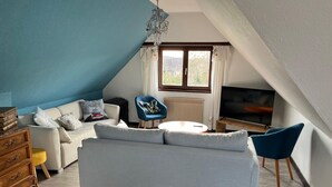 A cozy living room with a sofa, a wooden dresser, a blue chair, and a TV.