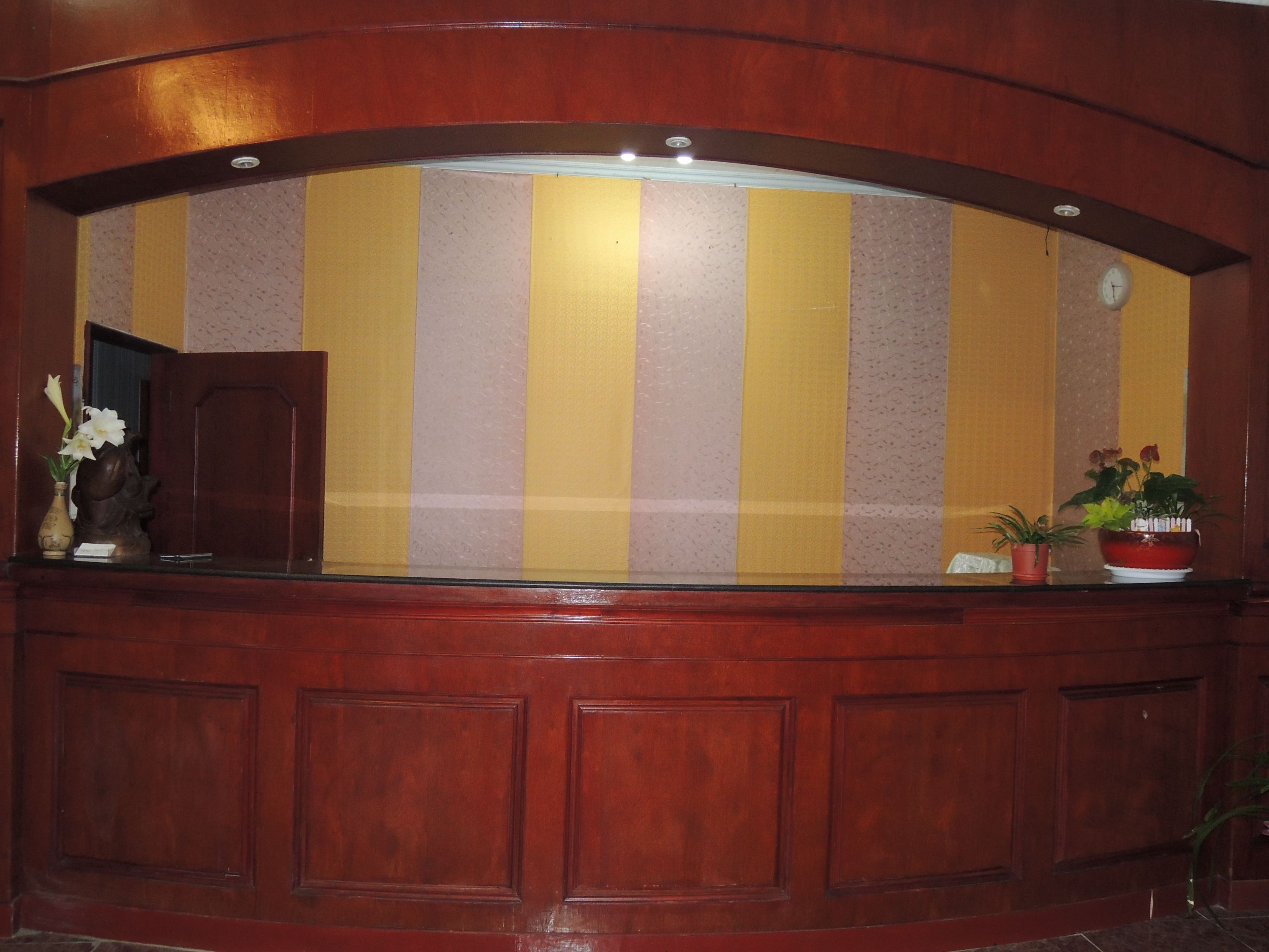 Una recepción con pared a rayas, un reloj y plantas en macetas.