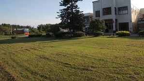 A building with a tiled facade and multiple windows, surrounded by a grassy area and trees. - Kinmen Laoye B&B (Jinhu)