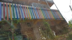 A building with a multi-story structure, featuring a series of vertical windows and a balcony with colorful railings. - You Ye De Lin B&B (Meishan)