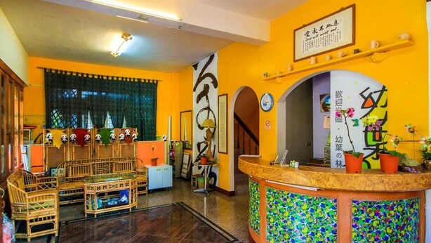 A reception area with a counter, chairs, and a decorative wall. - You Ye De Lin B&B (Meishan)