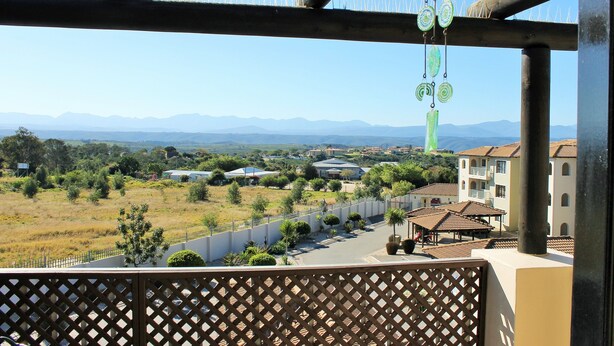 A balcony with a view of a rural landscape, including fields, trees, and distant mountains. - Santini Village 103 (Plettenberg Bay)