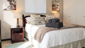 A neatly arranged bedroom with a bed, bedside lamps, and a nightstand. - Santini Village 103 (Plettenberg Bay)