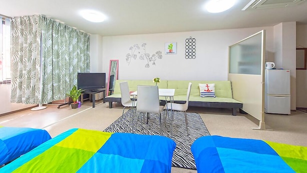 Een moderne woonkamer met een bank, stoelen, een televisie en een koelkast.