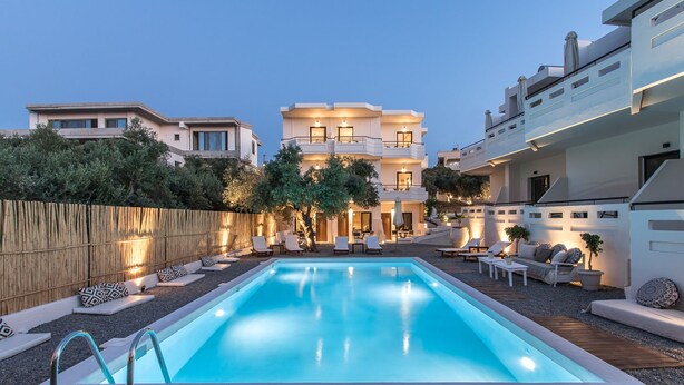 A modern pool area with a clear blue pool, lounge chairs, and a wooden deck. - Kanso Rooms (Chania)