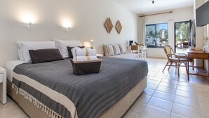 A modern hotel room with a large bed, a desk, and a view of the outdoors. - Kanso Rooms (Chania)