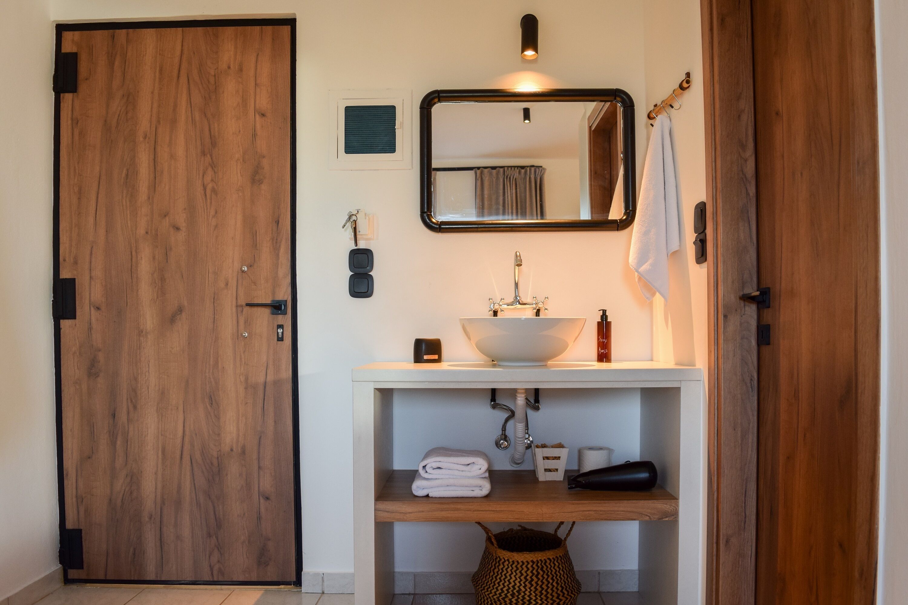 A bathroom with a wooden door, a white sink with a mirror above it, and a towel rack.