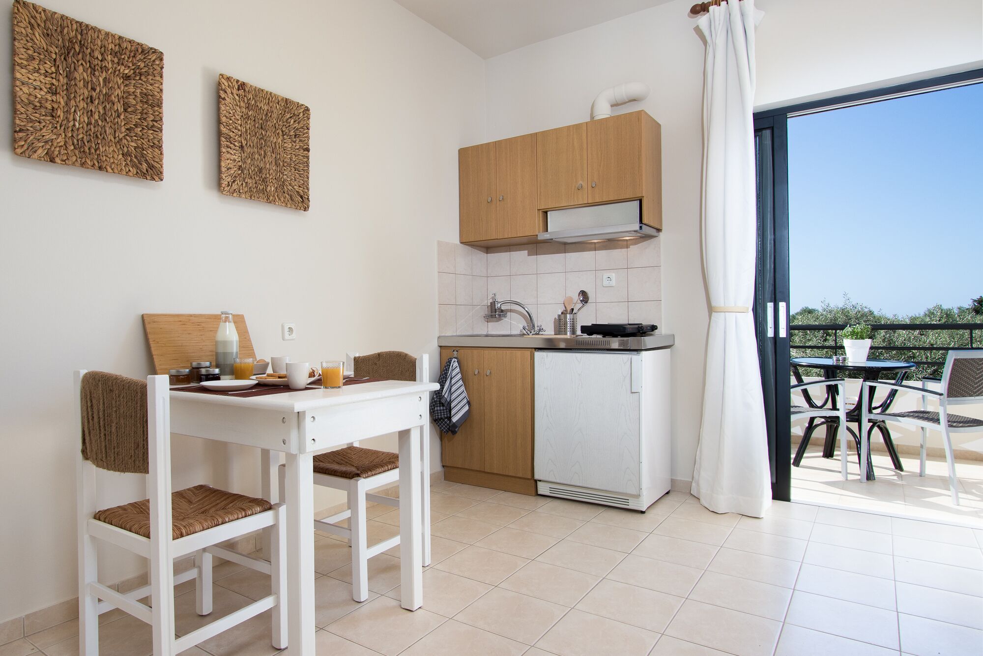Une cuisine compacte avec un coin repas, un petit réfrigérateur et une vue sur l’extérieur.