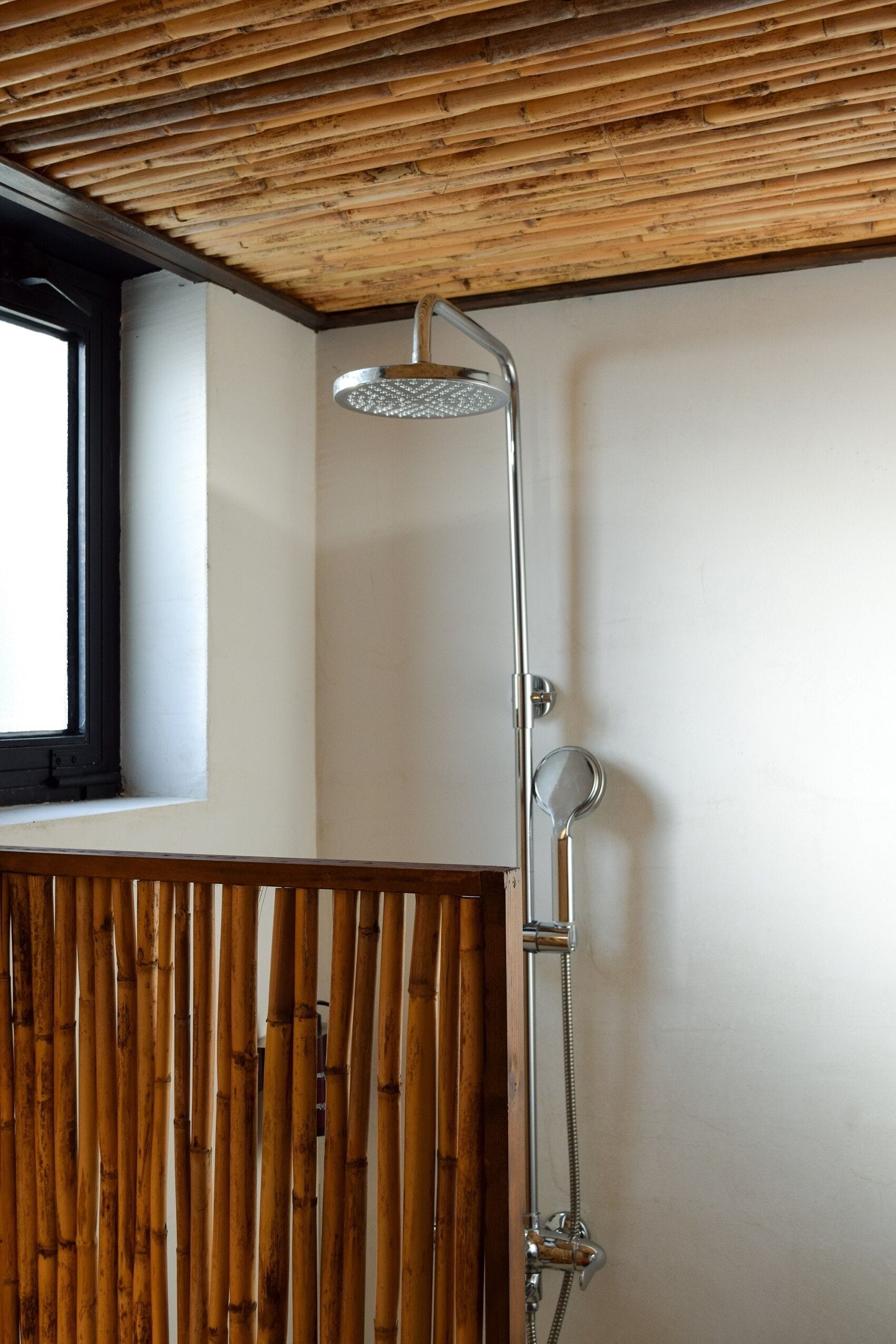 A shower with a wooden ceiling and a window to the left.