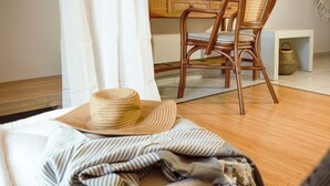 A cozy room with a wooden floor, a striped blanket, and a straw hat on a couch. - Kanso Rooms (Chania)